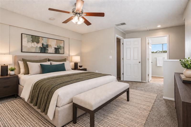Bedroom with furniture including bed, plant, and bedside table with lamp