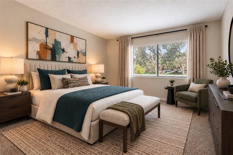 Bedroom with furniture including bed, plant, and bedside table with lamp