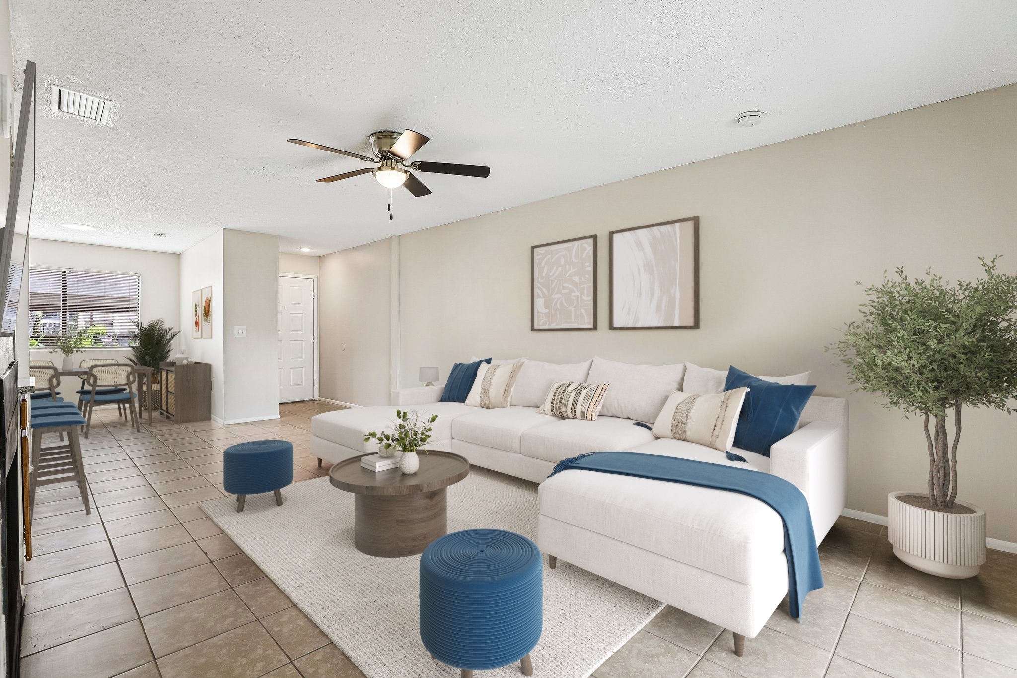 Living room with furniture including couch, coffee table, dining table, and bar stools.