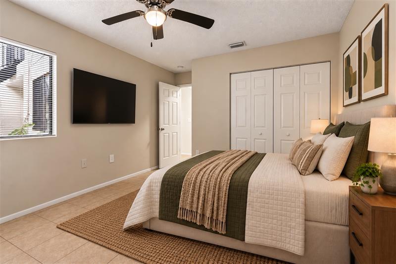 Bedroom with furniture including bed, plant, and bedside table with lamp.