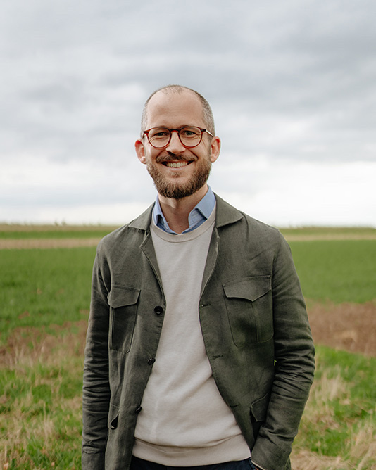 Geschäftsführer Konstantin Erol steht auf eine grünen Wiese.