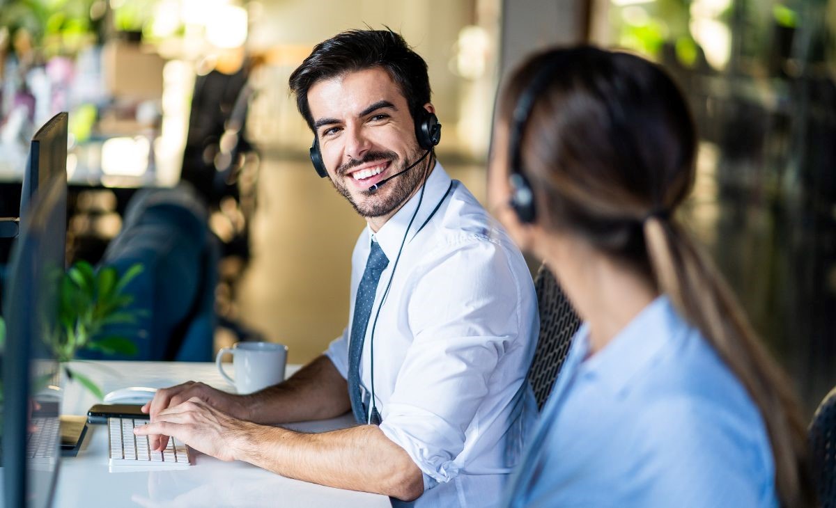a man working on a PC a smiling to a woman