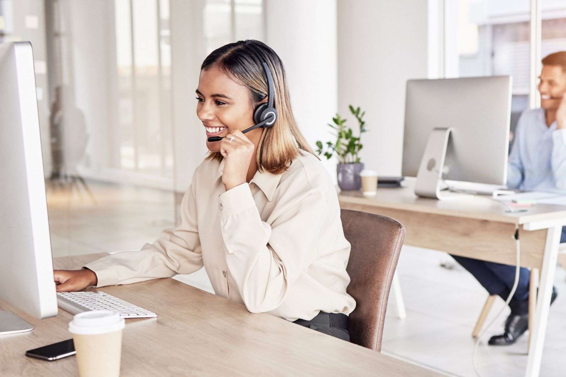 a woman and man talking on headphones and working on PC