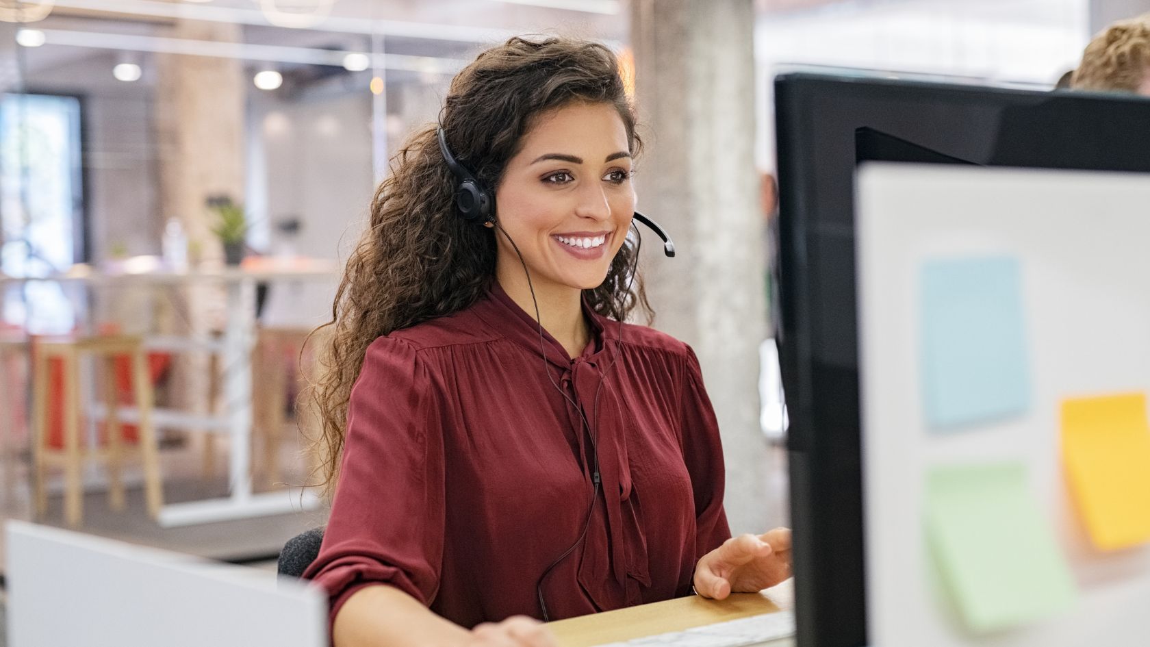 woman talks with headphones and works on PC