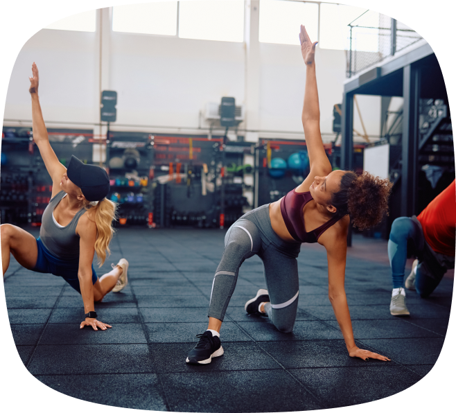 Three people performing side stretches on gym floor mats during a workout session.