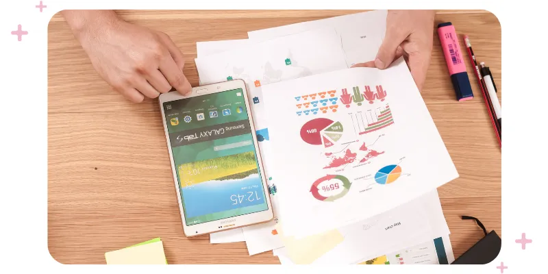 A person working, with a tablet and papers spread on their desk.