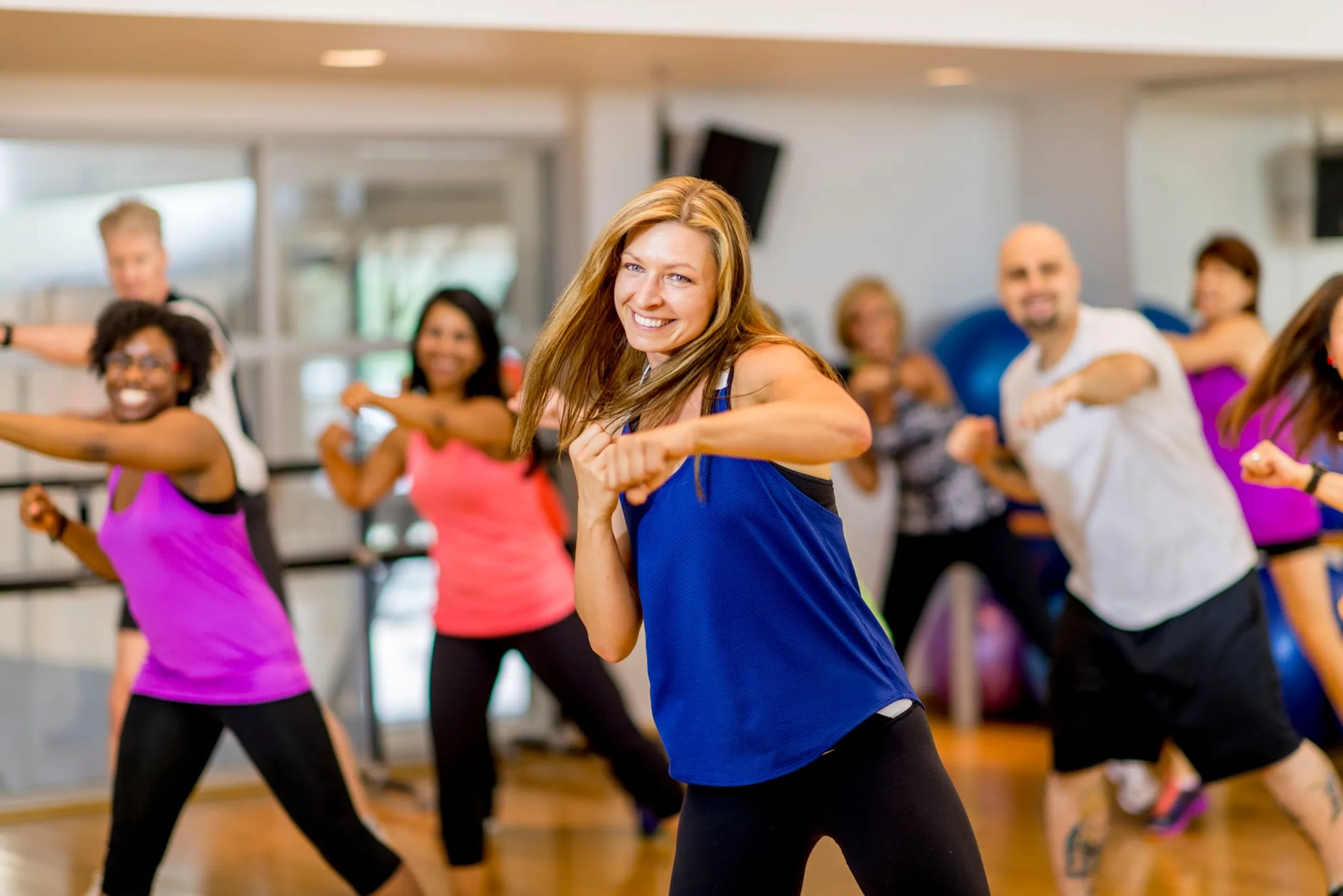 A fitness coach leading a class with happy clients in the background