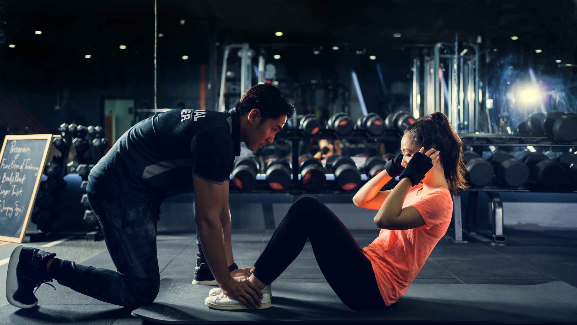 A personal trainer helps a personal training client through a workout.