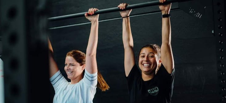 two girls at the gym holding onto a bar | Photo Credit: CrossFit Pembrokeshire Tenby