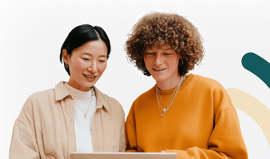 Deux personnes souriantes regardant un ordinateur portable ensemble.