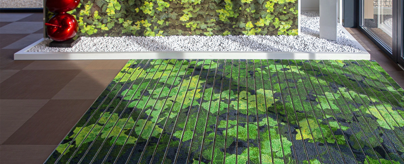 EMCO MAXIMUS IMAGE custom printed entrance mat with green leaf design in front of a living wall