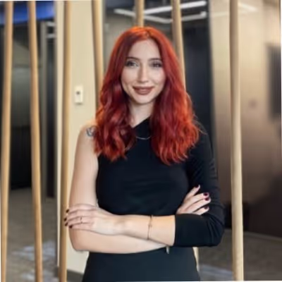 Kolları çapraz yapılmış, dalgalı kırmızı saçlı siyah kıyafet giymiş genç kadın.