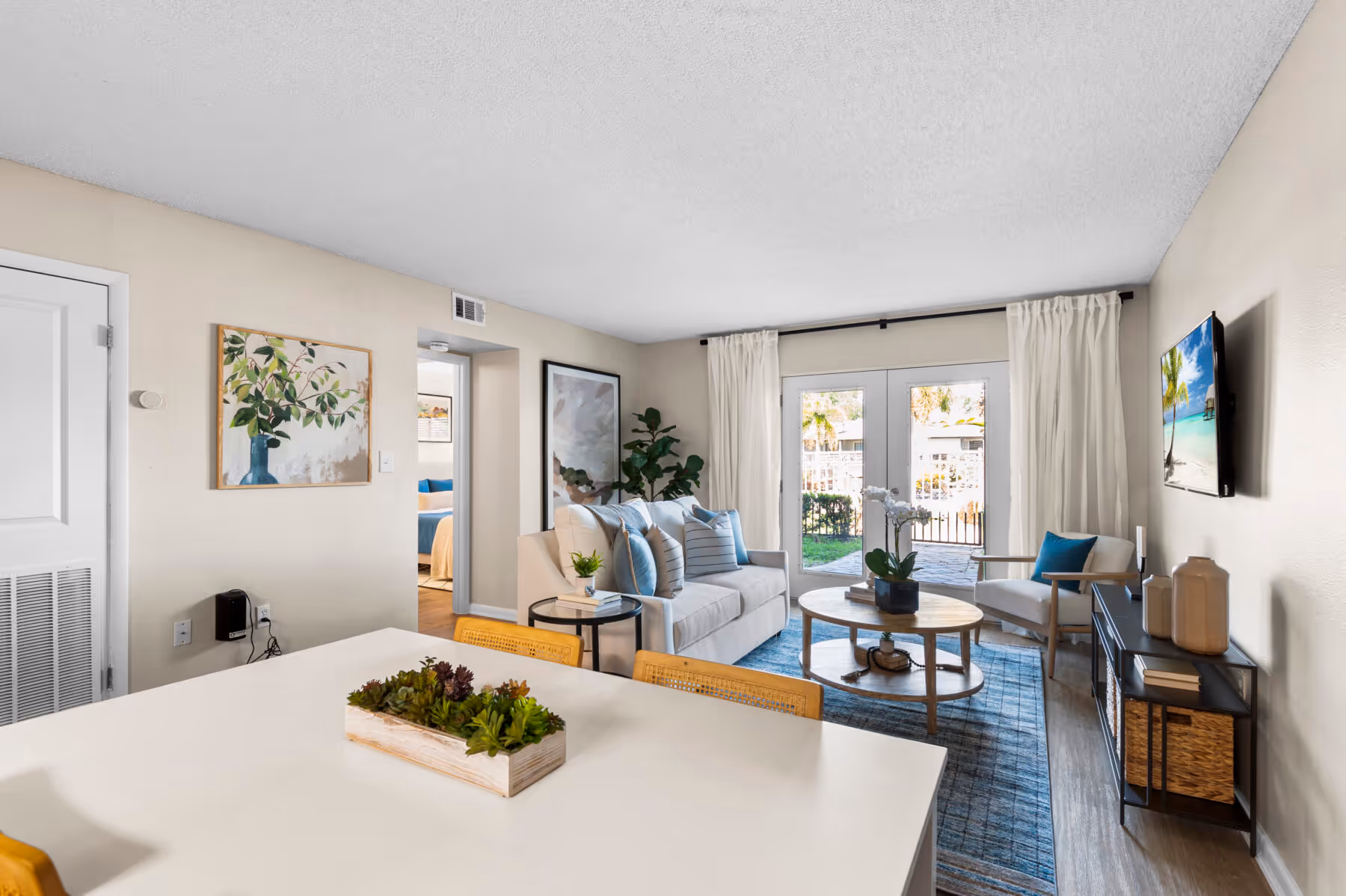 View of Living area with sofa, tv, coffee table from dining area with table and chairs