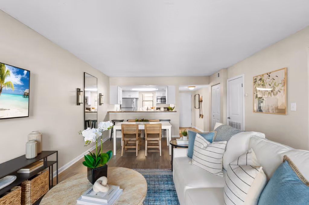 Wide view of living area with sofa, tv, and coffee table and view into dining area and kitchen