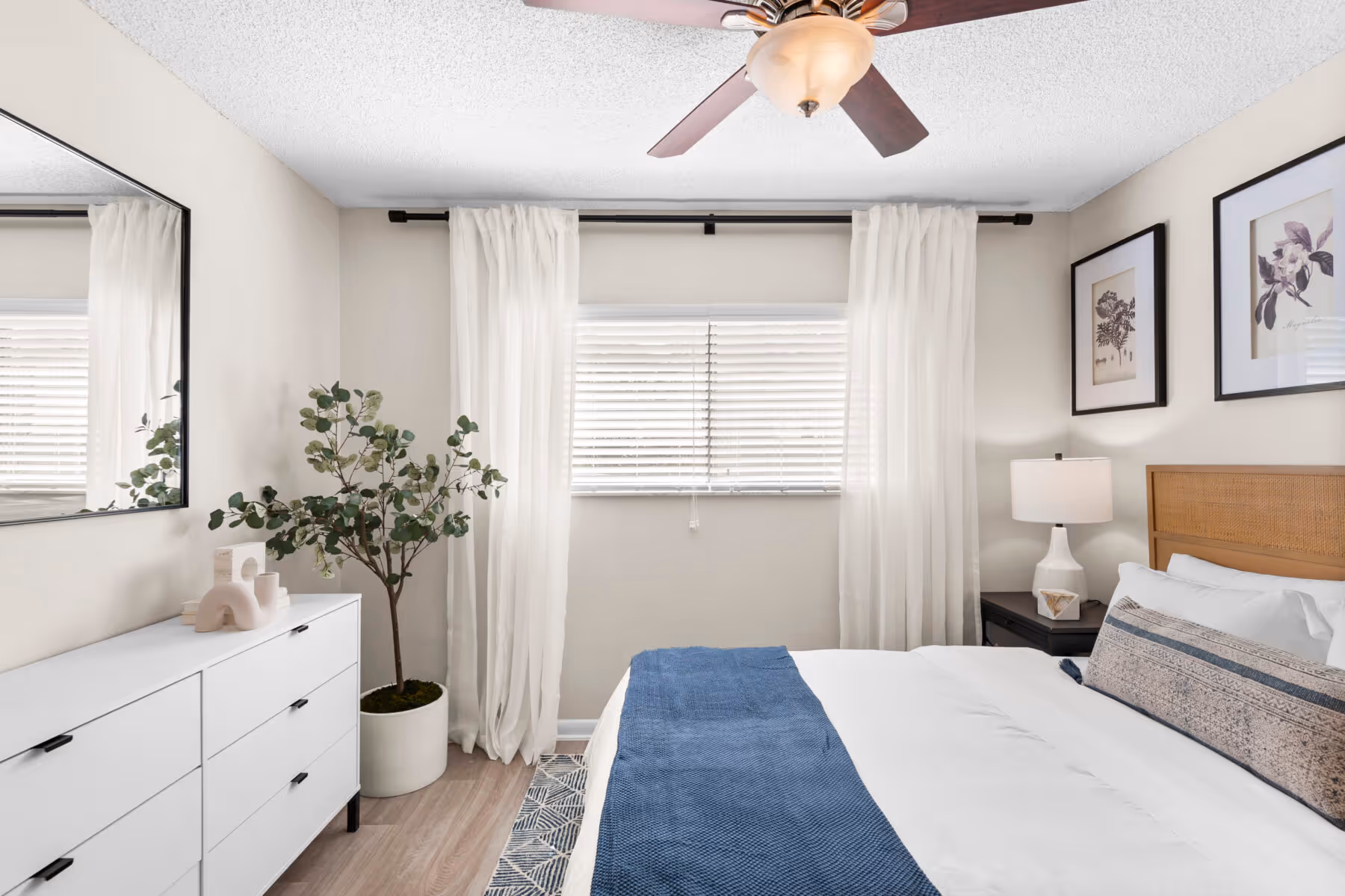Bedroom with bed, dresser, wall art, ceiling fan, and large window