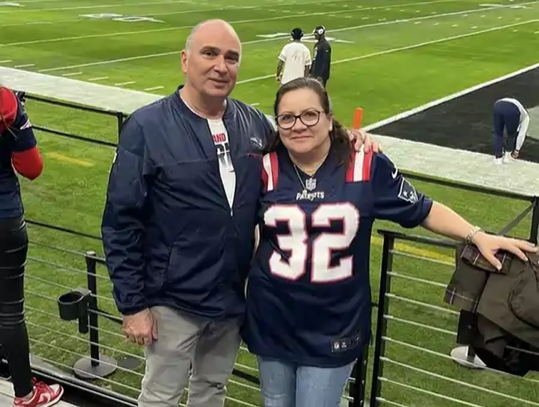 A man and a woman posing for a picture at a football game.