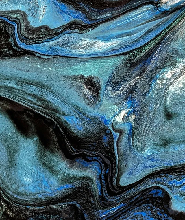Abstract swirled pattern with black, blue, and gray tones resembling marbled textures.