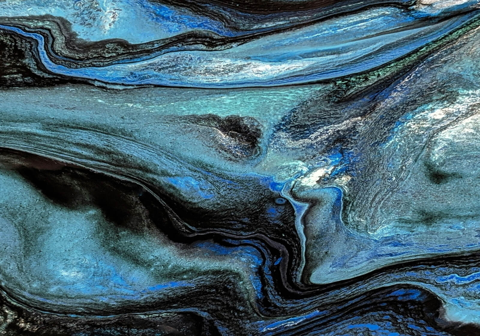 Abstract swirled pattern with black, blue, and gray tones resembling marbled textures.