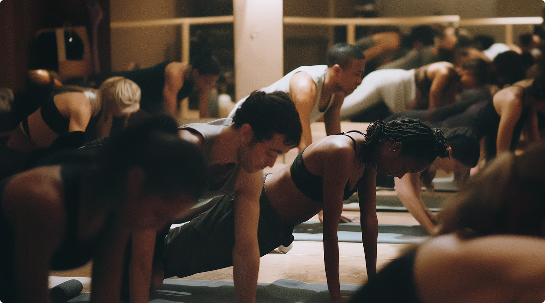 Group of diverse people in workout clothes doing push-ups in a gym fitness class.