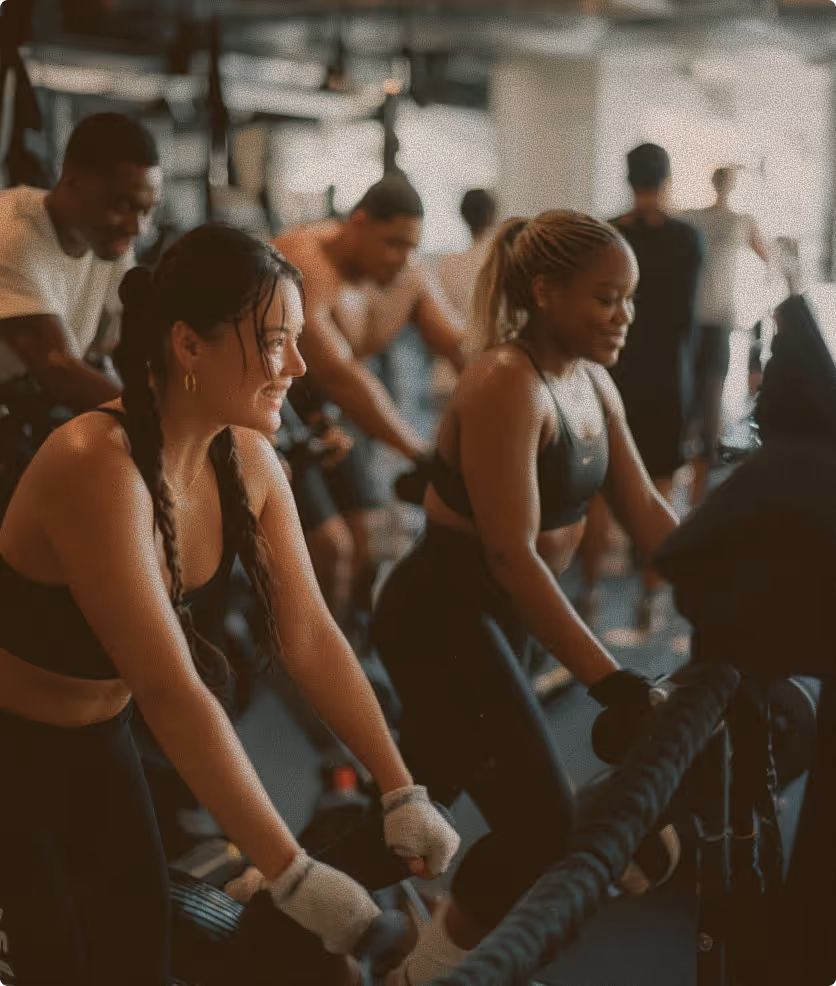 Diverse group of people exercising with battle ropes in a gym setting.