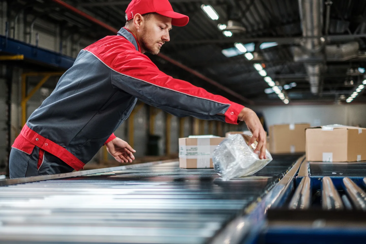 A worker placing a parcel onto a packing conveyor in a fulfilment centre.