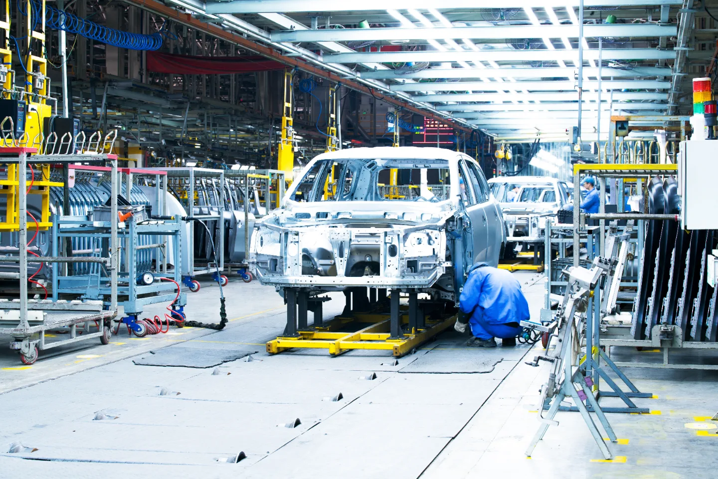 Vehicle bodies moving along an automotive assembly line inside a manufacturing plant.