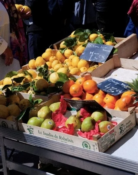 Citrons, oranges et poires en caisses au marché avec étiquettes de prix écrites à la main.