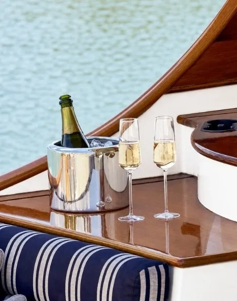 Seau à glace avec bouteille et deux flûtes de champagne sur une table en bois yacht