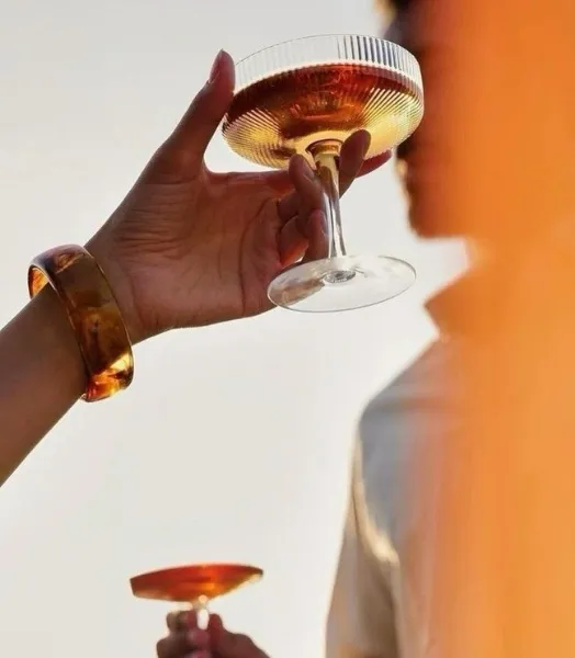 Two hands toasting with cocktail glasses, one pink and the other golden, in Saint-Tropez.