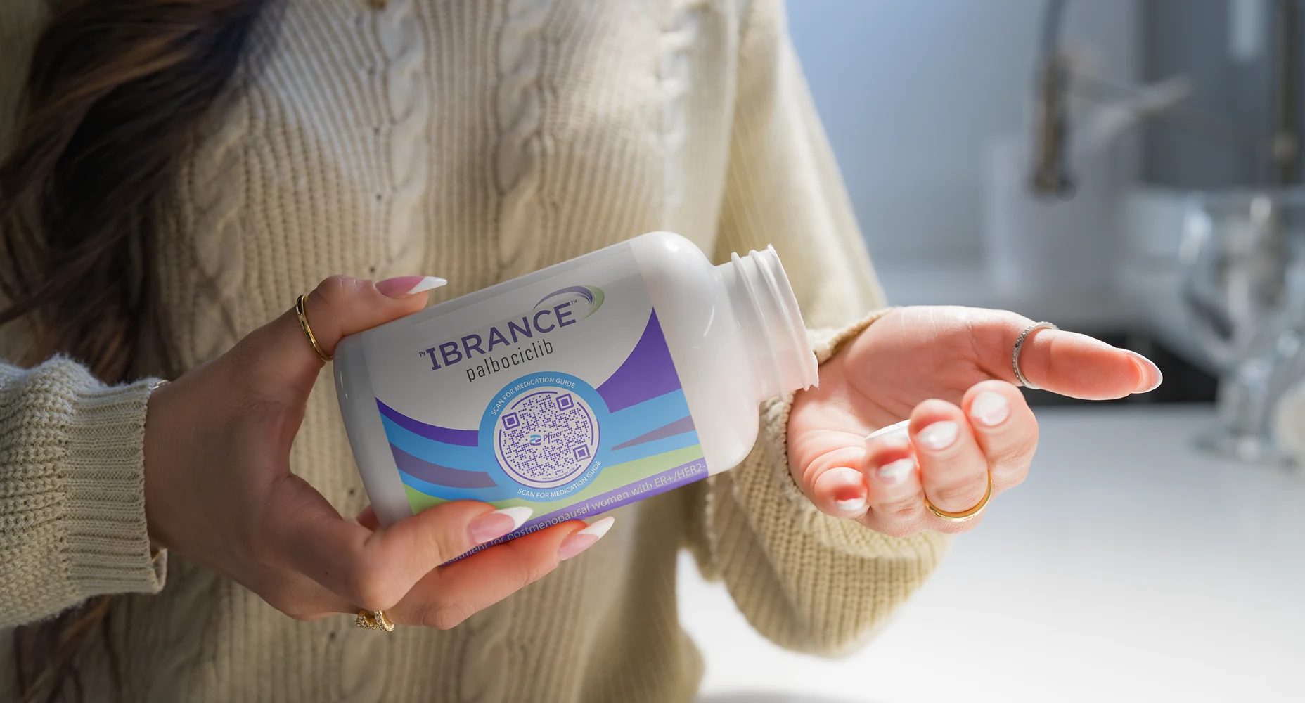 Person holding an open IBRANCE palbociclib medication bottle with a Flowcode on the label.