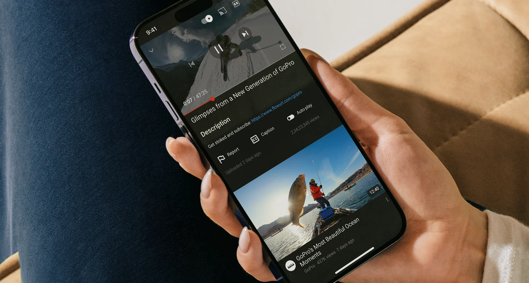 Hand holding a smartphone displaying a paused GoPro video titled 'Glimpses from a New Generation of GoPro' with a FlowURL