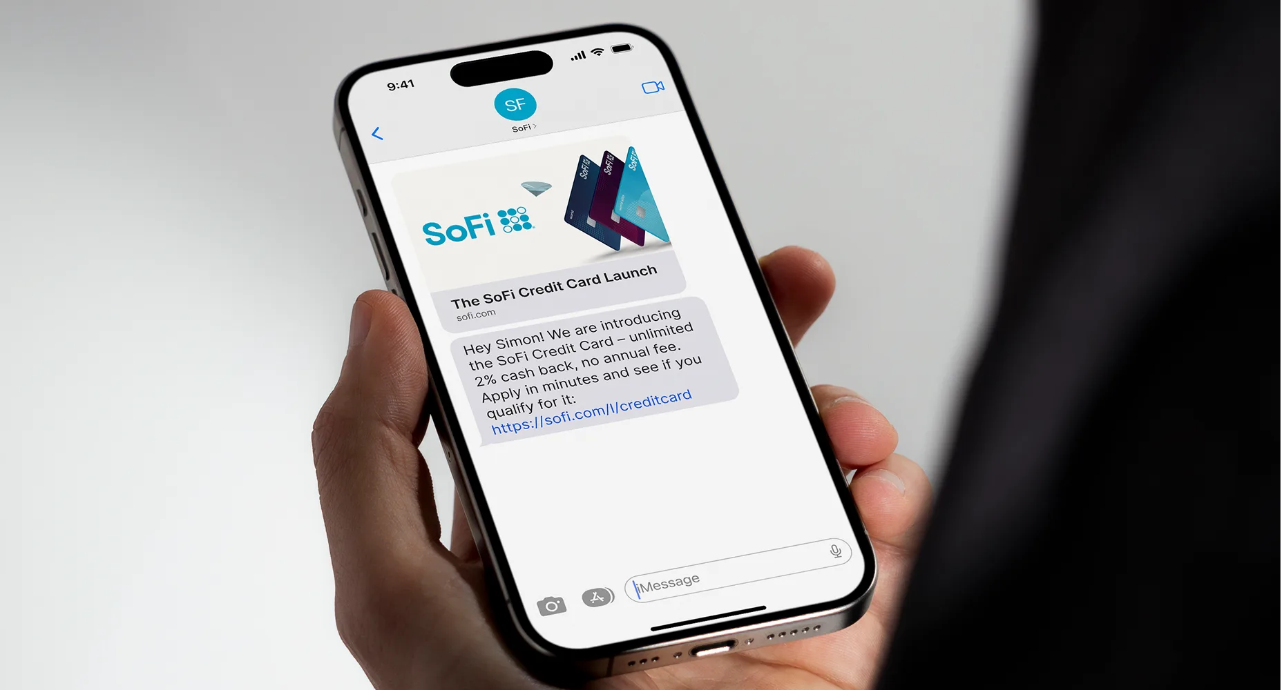 Hand holding a phone displaying a SoFi credit card launch message with  a FlowURL for cash back and no annual fee offer.