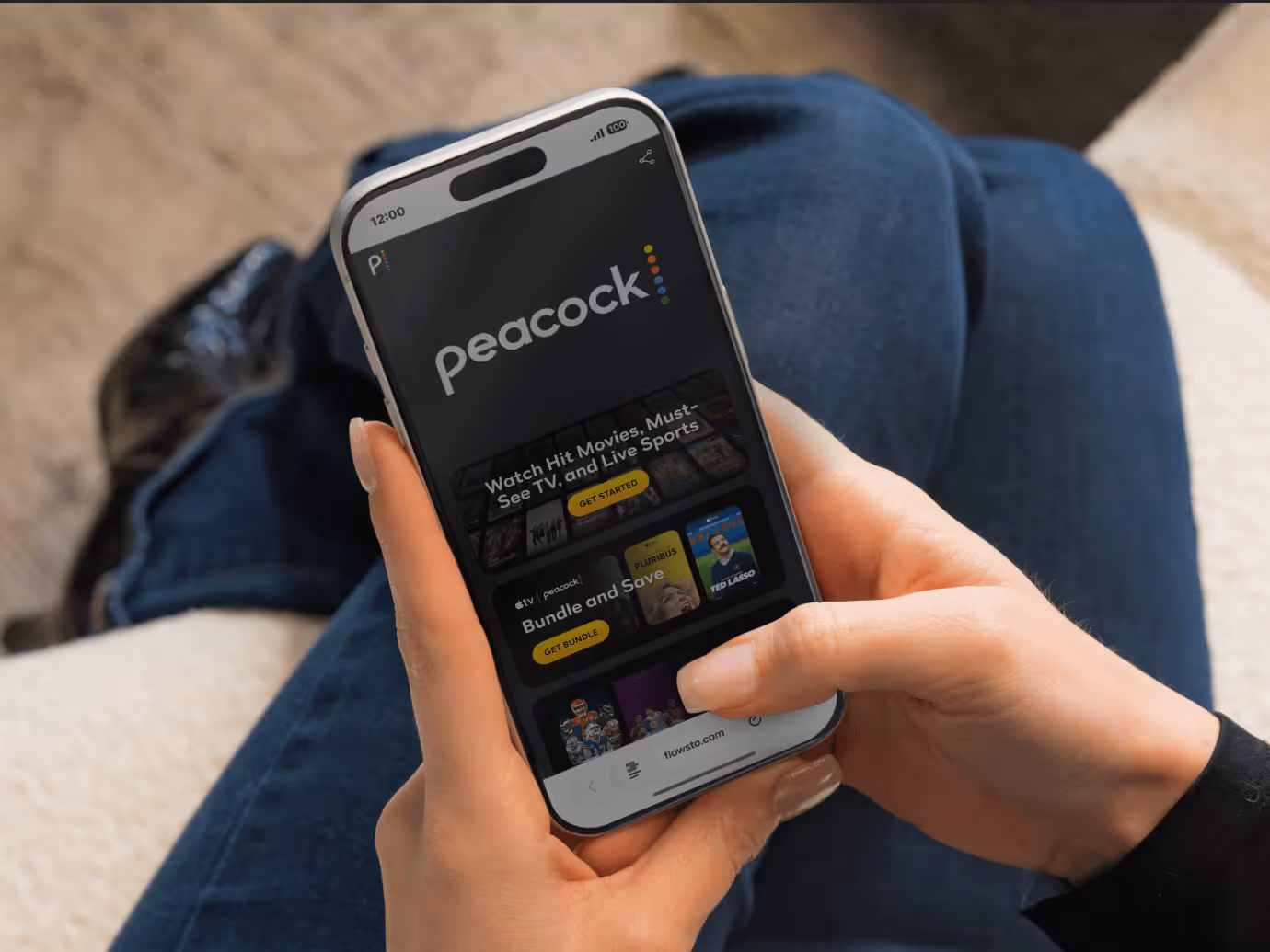 Person holding smartphone displaying Peacock FlowHub with movie and TV options.