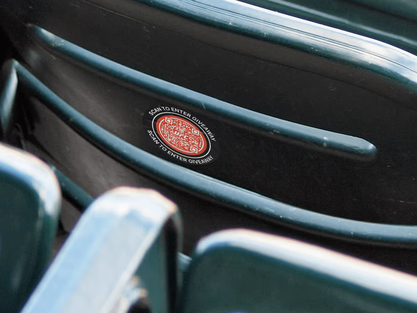 Row of empty stadium seats with a red Flowcode tag on seat back that reads Scan to Enter Giveaway.