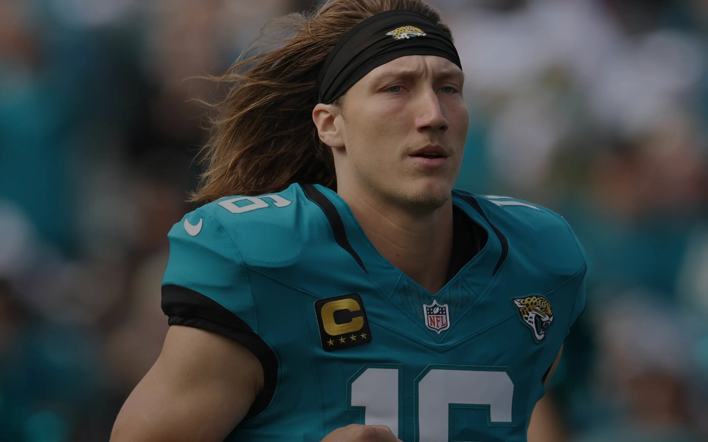 Jacksonville Jaguars football player with long hair wearing teal uniform and captain patch.
