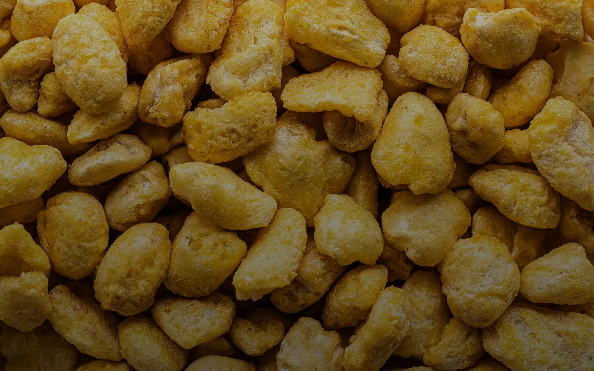Close-up of multiple yellow puffed corn snack pieces.