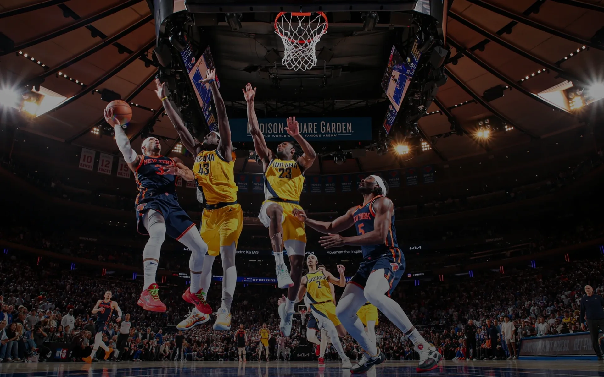 Basketball players competing near the hoop at Madison Square Garden.