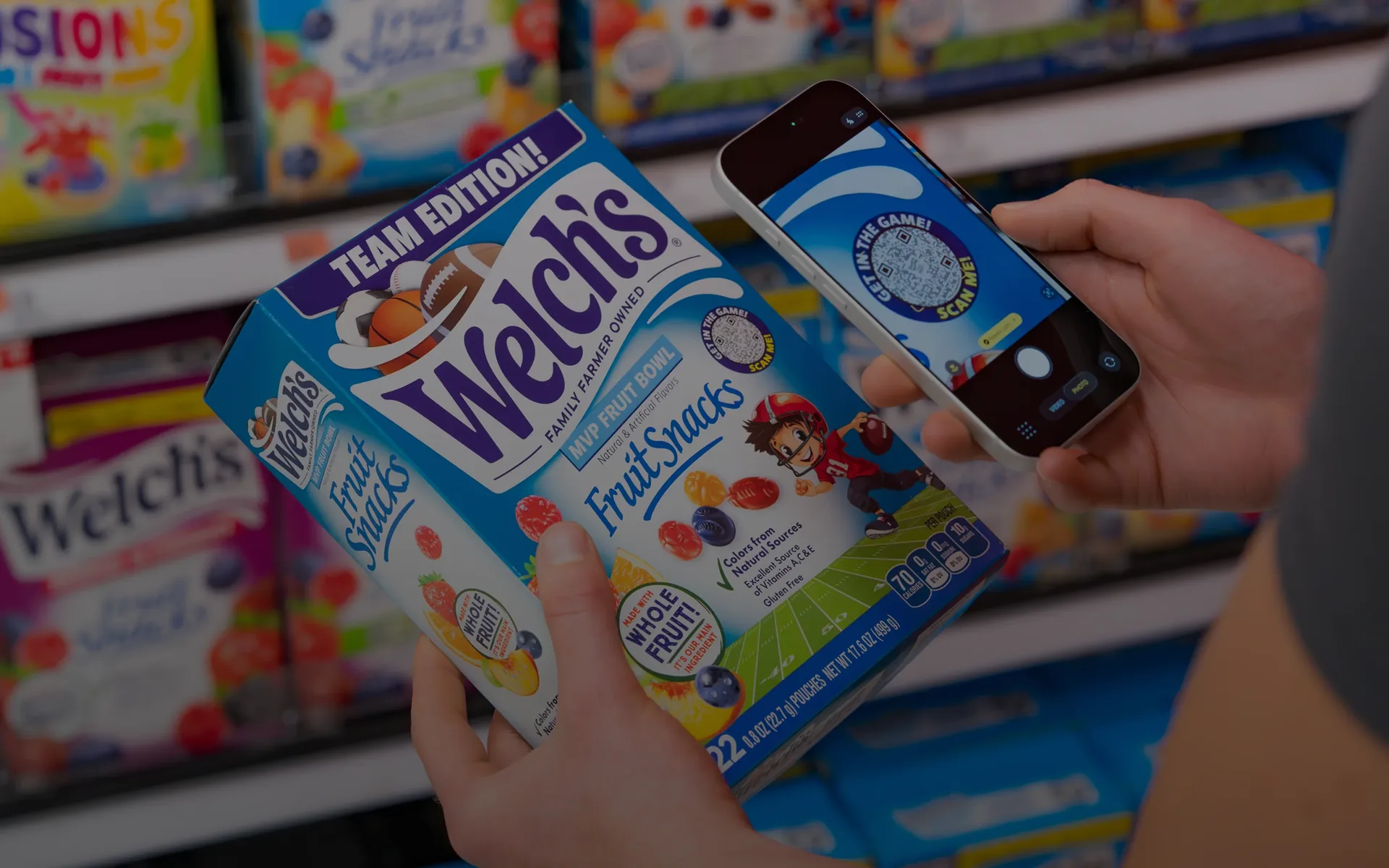 Person scanning a Flowcode on a box of Welch's Team Edition Fruit Snacks with a smartphone in a store.