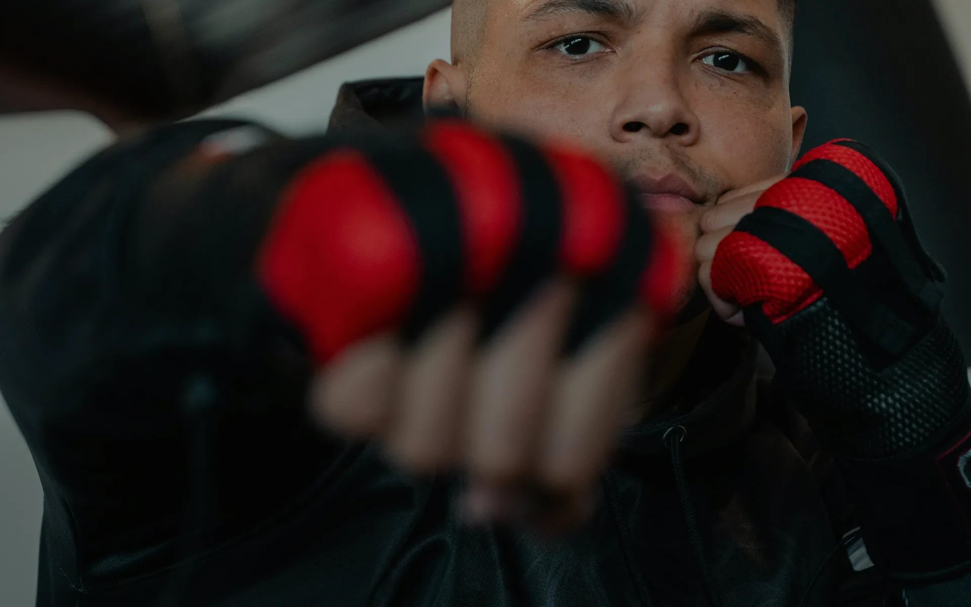 Close-up of a person wearing black and red boxing gloves holding fists up in a fighting stance.