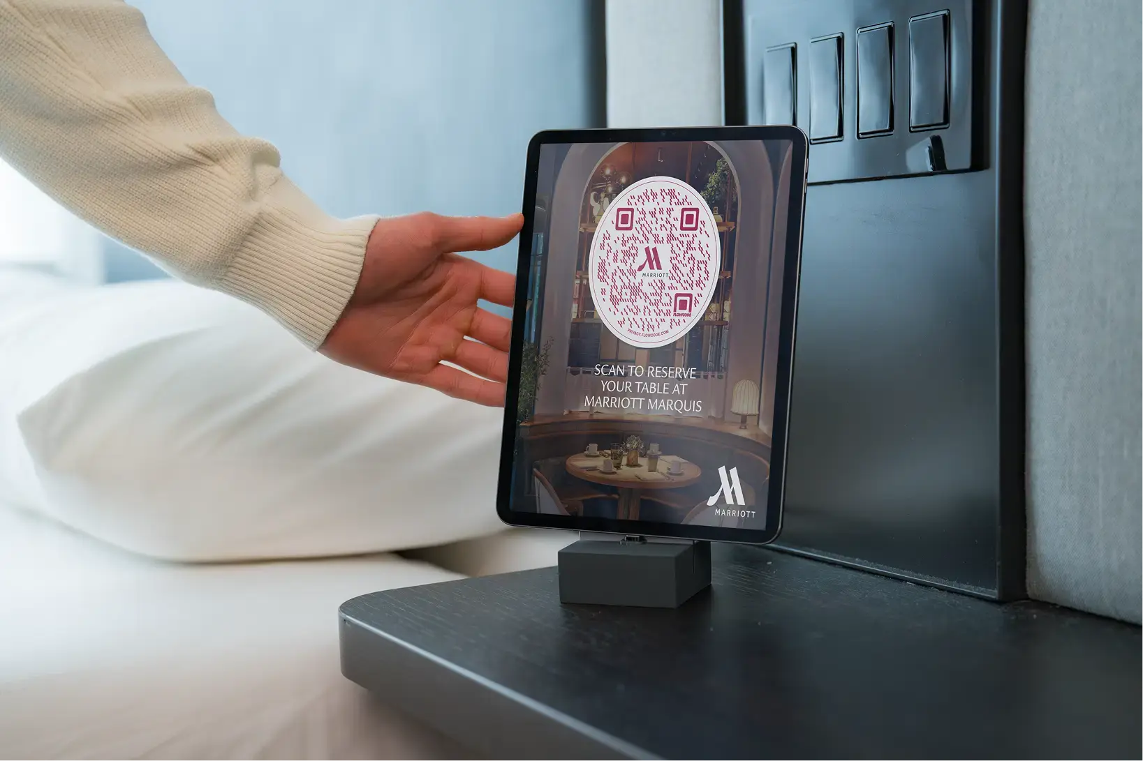 Hand approaching a tablet displaying a Flowcode to reserve a table at Marriott Marquis.