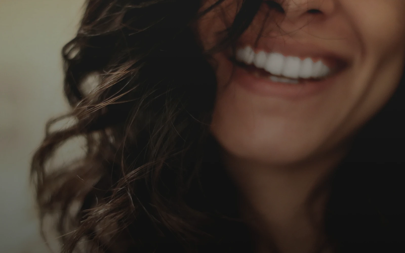 Close up of a woman with dark brown hair smiling, showing from the nose down just past her chin.