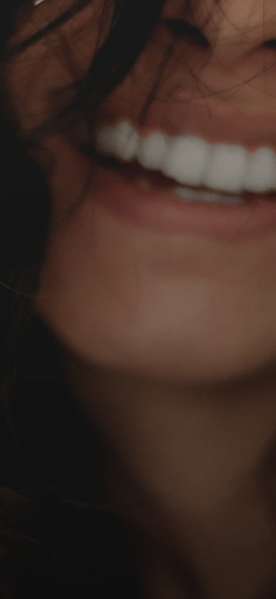 Close up of a woman with dark brown hair smiling, showing from the nose down just past her chin.
