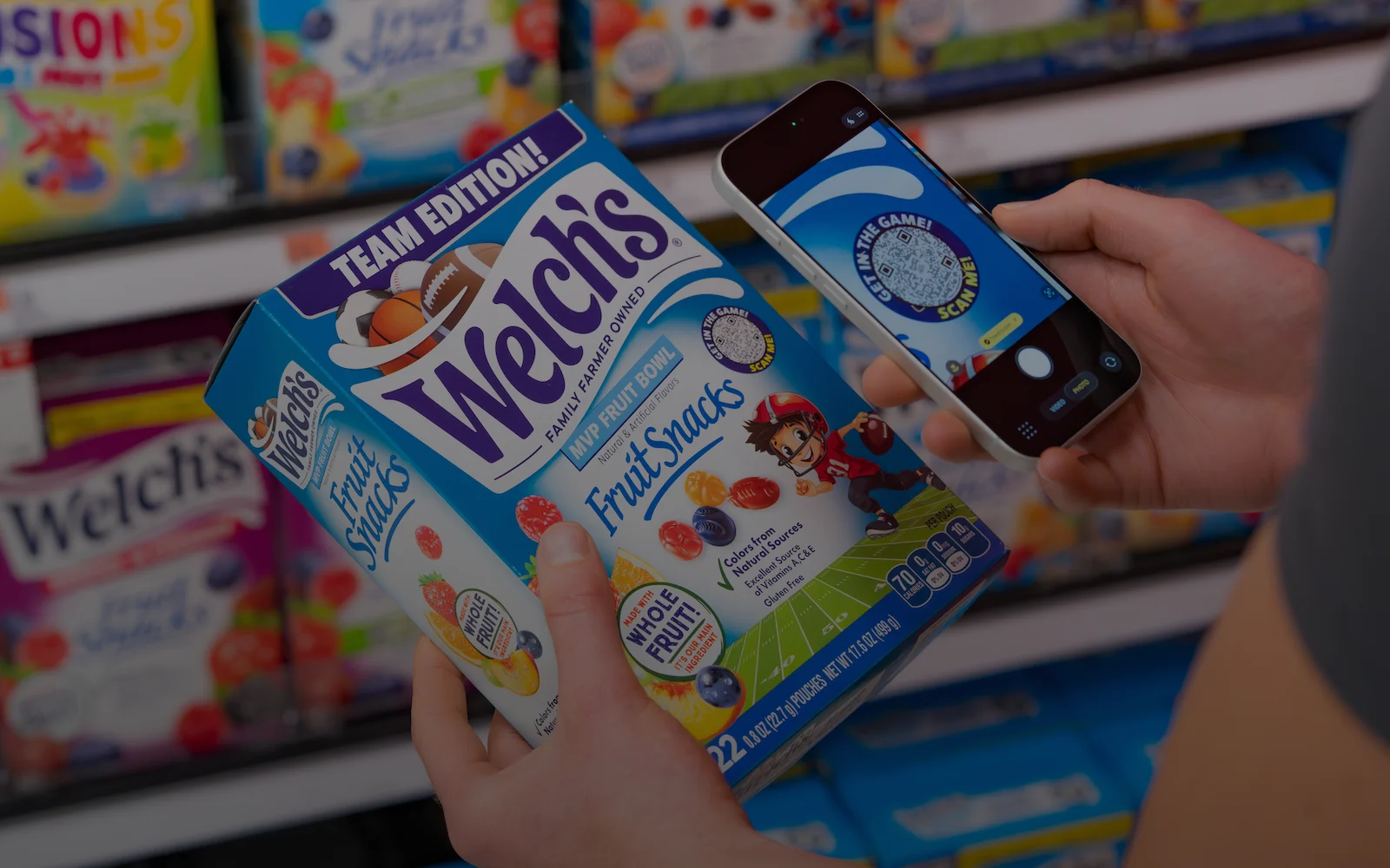 A Welch's Fruit Snack box is being scanned in shopping aisle at grocery store.