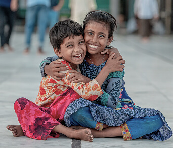Two children hugging and laughing together outdoors