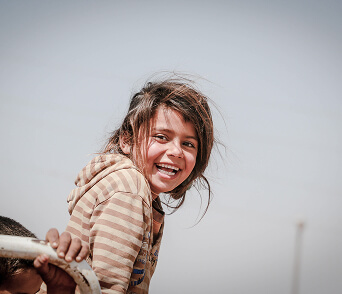 Girl smiling while looking back over her shoulder outdoors