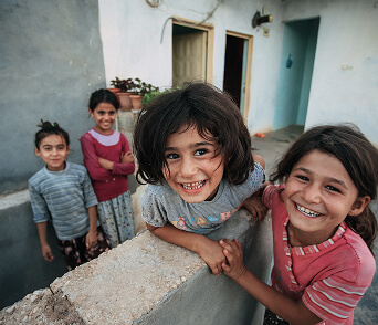 Group of children smiling together outdoors near a building