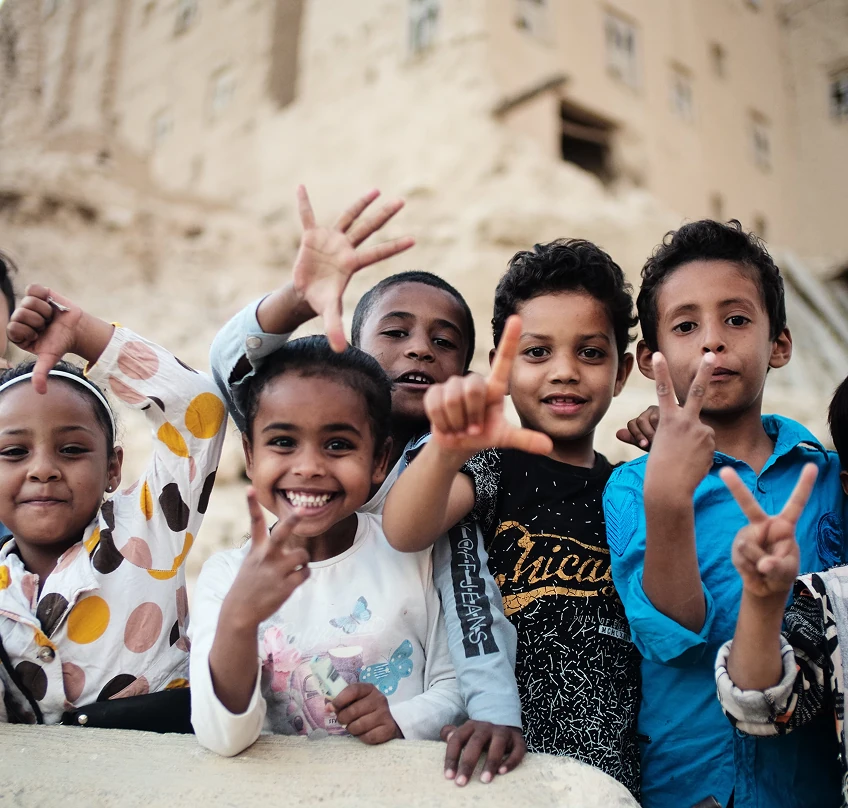 Group of smiling children waving and posing together outdoors