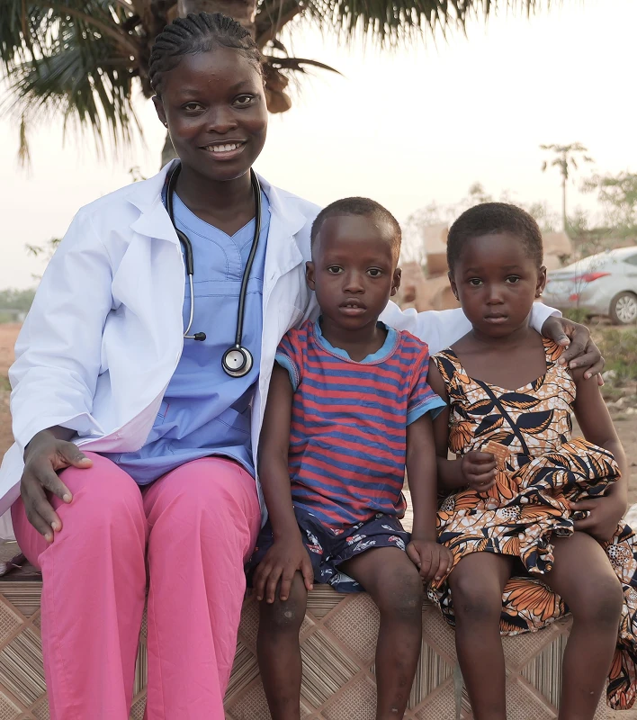 Three children sitting together outdoors, smiling