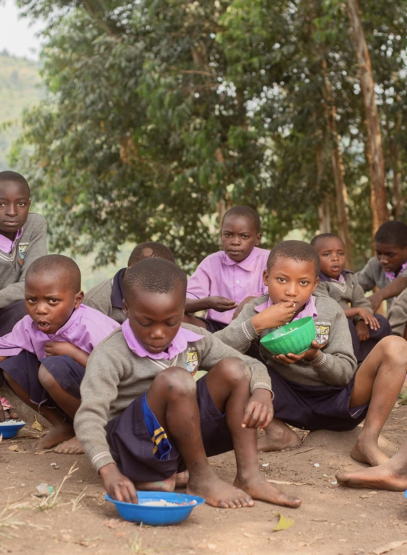 Group of children sitting outdoors eating from bowls