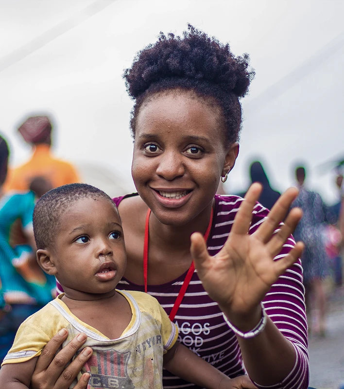 Woman waving with a child in her arms outdoors